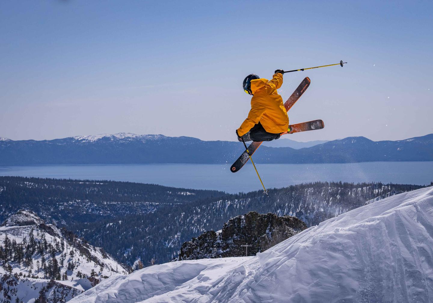 Skier in yellow jacket jumping over lake Tahoe