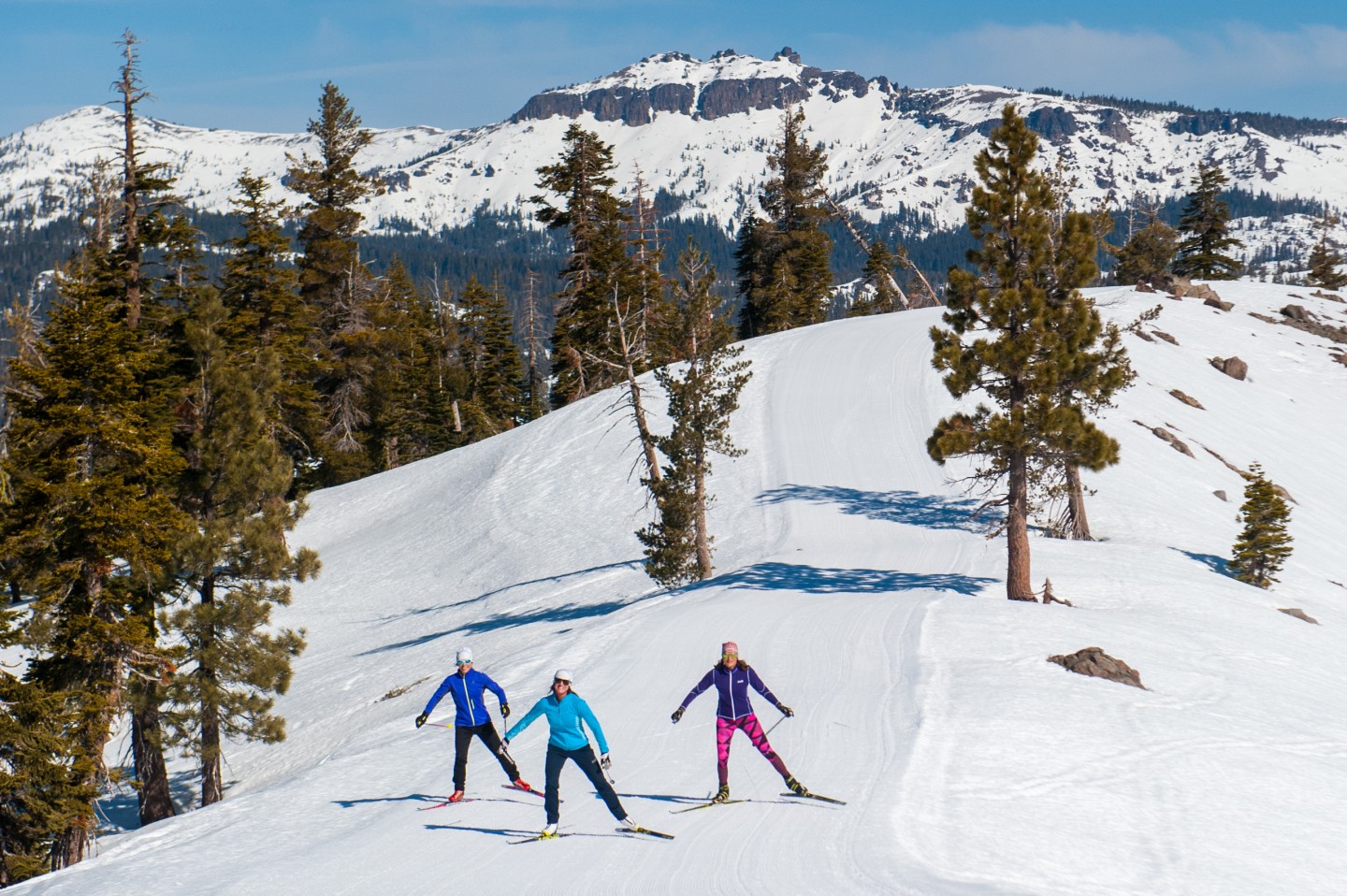 Three people cross country skiing along a ridge